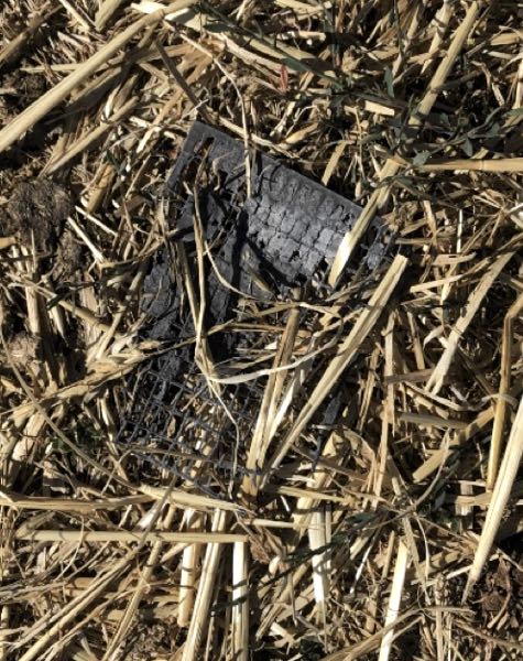 Image of hay spread on ground with part of broken battery